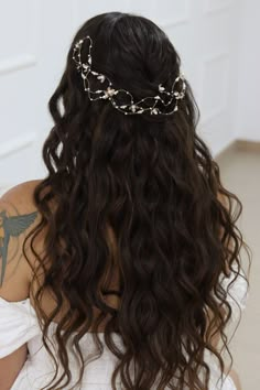 the back of a woman's head wearing a gold chain and pearl hair piece