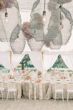 the inside of a tent with tables and chairs set up for a wedding reception in front of large windows