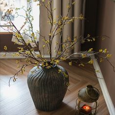 a vase filled with yellow flowers sitting on top of a wooden floor next to a lantern