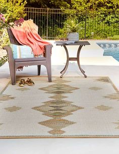 a patio area with a table, chair and pool in the backgroung