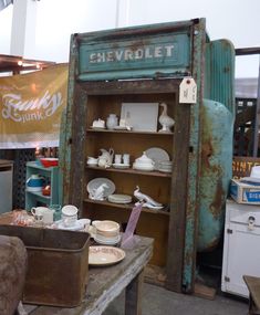 an old metal cabinet filled with dishes and other items in a room full of junk