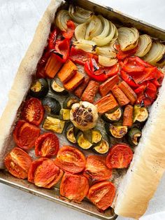 an overhead view of roasted vegetables in a baking pan on a white tablecloth,