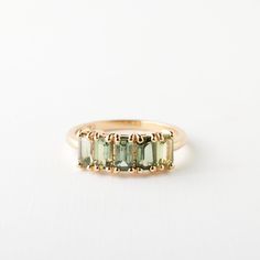 a gold ring with green stones on it