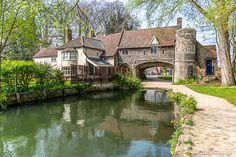 a river running through a lush green park next to a stone bridge over it's water