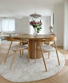 a dining room table with chairs and a rug on the floor in front of it