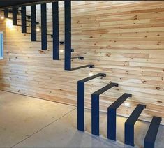 an empty room with wooden walls and black metal railings on the wall is lit by recessed lights