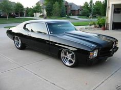 a black muscle car parked in a driveway