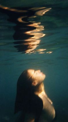 a woman is swimming in the water with her head above the water's surface