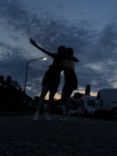 two people hugging each other in the street at night with their arms around one another