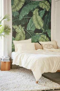 a bedroom with a large green leaf wall mural behind the bed and rug on the floor