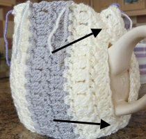 a crocheted coffee cup holder with two cups in it and three arrows pointing to the top