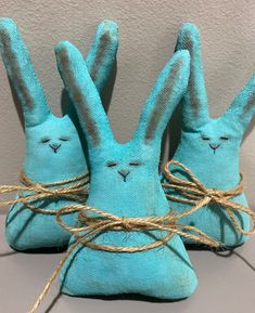 two blue stuffed bunnies tied up to each other with twine on the ends