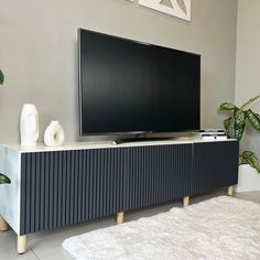 a flat screen tv sitting on top of a wooden cabinet in front of a white rug