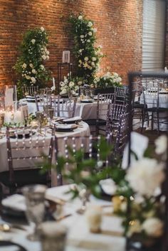 the tables are set up with white flowers and greenery for an elegant wedding reception