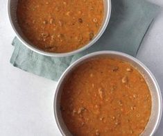 two white bowls filled with soup sitting on top of a table next to each other