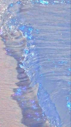 an ocean wave is coming towards the shore with blue lights on it's side