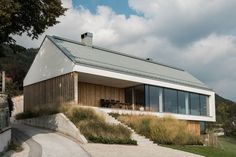 a modern house on a hillside with grass and trees