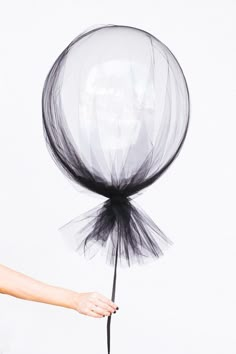 a woman holding a black and white balloon with tulle on it's tail