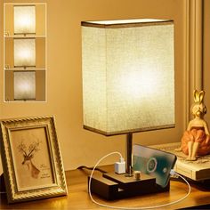 a lamp sitting on top of a wooden table next to a framed picture and an electronic device