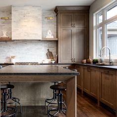 a large kitchen with wooden cabinets and stools in front of the counter top is shown