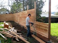 a man is using a power drill to build a fence