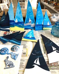 several blue sailboats are sitting on top of newspaper pages with other items around them