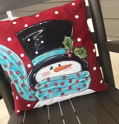 a snowman pillow sitting on top of a wooden chair