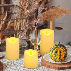 four candles are sitting on a table next to a plate with a pumpkin and gourmet food