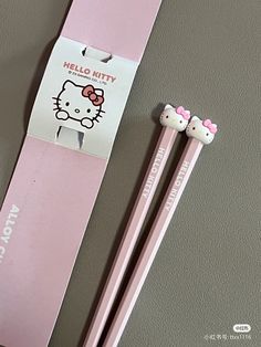 two pink hello kitty pencils sitting next to each other on a gray table top