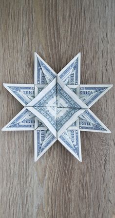 an origami star made out of dollar bills on a wooden table with wood grain