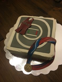 a cake with a ribbon around it on top of a white plate and wooden table