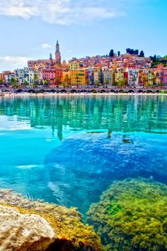 the water is crystal blue and clear with buildings in the backgrouds behind it