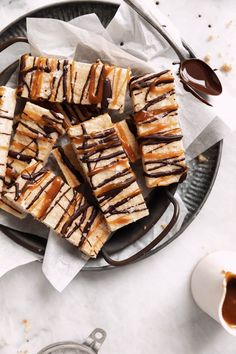 several pieces of cake on a plate with chocolate drizzled over them and sitting next to a cup of coffee