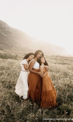 three women are standing together in a field