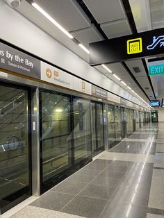 an empty subway station with glass doors and signs above the doors that say exit by the bay