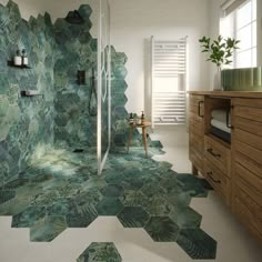 a bathroom with green tiles on the floor and walls, along with a wooden cabinet