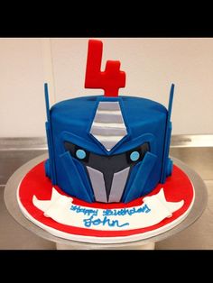 a blue and red cake sitting on top of a metal table next to a white wall