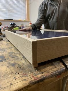 a man standing in front of a wooden box on top of a workbench