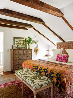 a bedroom with white walls and wooden beams