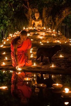 a man in an orange robe is surrounded by candles