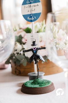 there is a small figurine on top of a table with flowers in the background