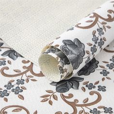 a roll of toilet paper sitting on top of a flowery wallpaper covered floor