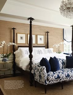 a bedroom with four poster bed, chandelier and blue couch in the middle