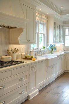 a large kitchen with white cabinets and wood flooring, along with an island in the middle