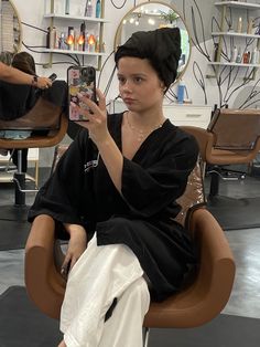 a woman sitting in a chair holding a cell phone