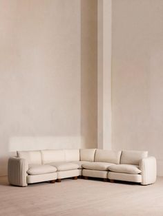 a white couch sitting on top of a hard wood floor next to a tall wall