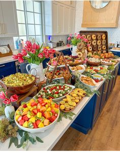 a table filled with lots of food on top of a kitchen counter next to flowers