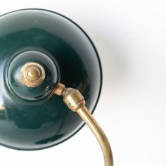 a green lamp with a gold handle on a white background