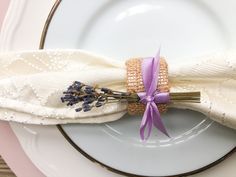 a white plate topped with a purple flower and a lavender boutonniere on top of it