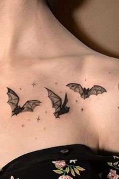 a woman's chest with three bats flying in the sky and stars on it